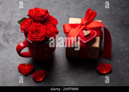 Rosenblüten in Kaffeetasse und Valentinstag-Geschenkbox Stockfoto