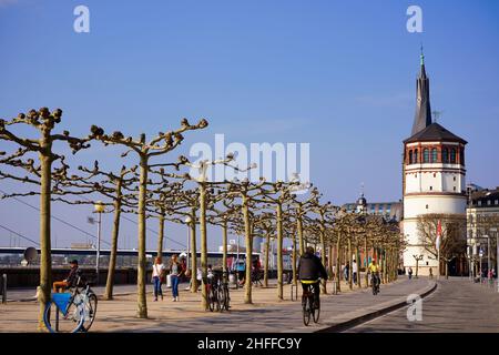 Rheinpromenade am Rathausufer in Düsseldorf an einem sonnigen Tag mit blauem Himmel. Historisches Schloss Turm im Hintergrund. Stockfoto