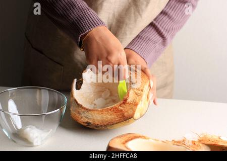 Weibliche Hand Geschöpft Kokosnussfleisch, Zubereitung Dessert Stockfoto