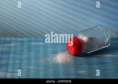 Umgedrehter Salzstreuer mit Salz auf der Seite, was einen übermäßigen Verbrauch darstellt Stockfoto