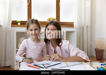 Kunstlehrerin kleines Mädchen abgelenkt von Zeichnung posiert vor der Kamera Stockfoto