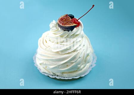 Baiser-Dessert mit Rahm und Beeren. Weißer Kuchen mit Feigen auf blauem Hintergrund. Ein Baiser-Kuchen aus der Nähe. Stockfoto