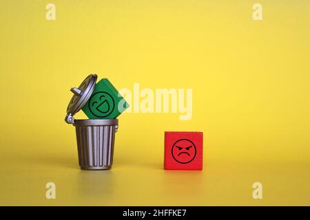 Schlechter Service, Feedback, Review-Konzept. „Angry Face“-Symbol und „Happy Face“-Symbol in einem Mülleimer Stockfoto