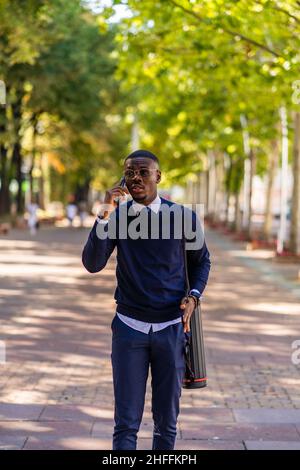 Ein gutaussehender afrikanischer Geschäftsmann telefoniert beim Gehen mit seinem Chef Stockfoto