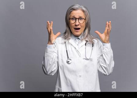 Angst vor einer Coronavirus-Pandemie, einer epidemischen Krankheit. Nahaufnahme eines Porträts einer Frau in Schutzkleid und Brille, die Angst vor der Kamera hat und ihre Hände in der Nähe ihres Kopfes hält Stockfoto