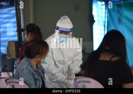 Bangkok, Thailand. 15th Januar 2022. Mitarbeiter des Gesundheitswesens der Stadtverwaltung von Bangkok, die PSA-Uniformen tragen und am 15. Januar 2022 am Bangkok Bus Terminal in Bangkok, Thailand, mit dem Rapid Antigen Test ein Wattestäbchen verwenden, um Proben von Personen zu sammeln, die Gefahr laufen, Covid-19 an öffentlichen Servicestellen sowohl im Drive-Thru- als auch im Walk-in-Format zu erreichen. (Foto von Teera Noisakran/Pacific Press/Sipa USA) Quelle: SIPA USA/Alamy Live News Stockfoto