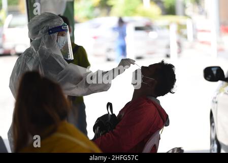 Bangkok, Thailand. 15th Januar 2022. Mitarbeiter des Gesundheitswesens der Stadtverwaltung von Bangkok, die PSA-Uniformen tragen und am 15. Januar 2022 am Bangkok Bus Terminal in Bangkok, Thailand, mit dem Rapid Antigen Test ein Wattestäbchen verwenden, um Proben von Personen zu sammeln, die Gefahr laufen, Covid-19 an öffentlichen Servicestellen sowohl im Drive-Thru- als auch im Walk-in-Format zu erreichen. (Foto von Teera Noisakran/Pacific Press/Sipa USA) Quelle: SIPA USA/Alamy Live News Stockfoto