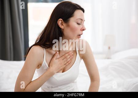 Porträt einer ungesunden jungen Frau, die viel hustet, an Husten leidet und Schmerzen in der Brust hat. Das kranke verzweifelte Weibchen hat eine Grippe. Kälte, Krankheit Stockfoto
