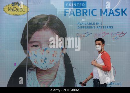 Bangkok, Thailand. 16th Januar 2022. Ein Mann, der eine Gesichtsmaske als vorbeugende Maßnahme gegen die Ausbreitung von covid-19 trägt, geht an einem Werbebildschirm vorbei, der außerhalb der Central World, dem Einkaufszentrum in Bangkok, Thailand, angezeigt wird. Kredit: SOPA Images Limited/Alamy Live Nachrichten Stockfoto