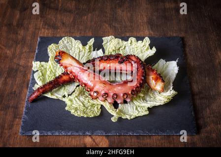 Trockener Krakenschenkel, nach der Tradition getrocknet, auf einem Kohlbett auf einem Steinteller serviert. Typisches Gericht der tropischen Küste von Granada. Stockfoto