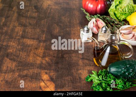 Holzhintergrund in abgenutzter brauner Farbe, auf einer Seite mit Gemüse, Öl, Salz und Pfeffer. Stockfoto