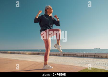 Lady trainiert an warmen Tagen an der Küste Stockfoto