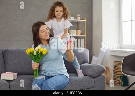 Glückliche Mutter bekommt am Muttertag Geschenke, Blumen und Grußkarten von ihrer Tochter Stockfoto