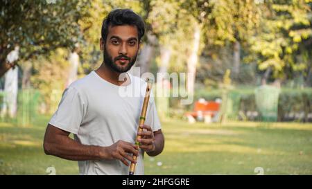 Bansuri-Spieler, der bei Sonnenschein im Park Musik spielt - Indian Flute Player Stockfoto