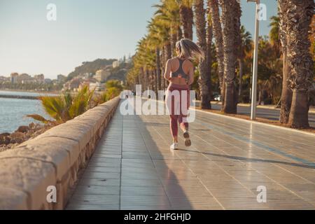 Sportliche, hübsche Frau, die aktiv am Wasser läuft Stockfoto