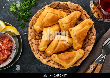 Gebratene Empanadas mit Koriander, Fleisch, Ei, Tomaten und Chilisauce auf schwarzem Hintergrund. Typisch chilenisches Gericht. Lateinamerikanische und chilenische Unabhängigkeit da Stockfoto