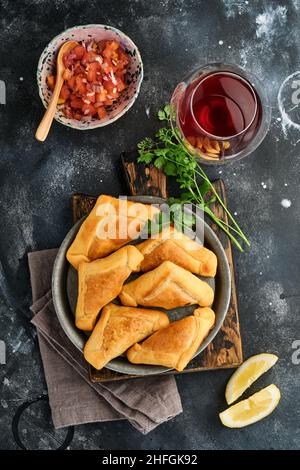 Gebratene Empanadas mit Koriander, Fleisch, Ei, Tomaten und Chilisauce auf schwarzem Hintergrund. Typisch chilenisches Gericht. Lateinamerikanische und chilenische Unabhängigkeit da Stockfoto