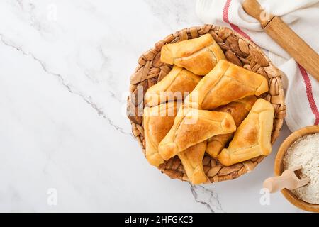 Gebratene Empanadas mit Koriander, Fleisch, Ei, Tomaten und Chilisauce auf weißem Hintergrund. Konzept des lateinamerikanischen und chilenischen Unabhängigkeitstages. Stockfoto