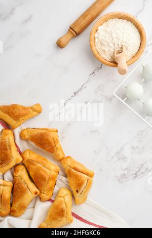 Gebratene Empanadas mit Koriander, Fleisch, Ei, Tomaten und Chilisauce auf weißem Hintergrund. Konzept des lateinamerikanischen und chilenischen Unabhängigkeitstages. Stockfoto