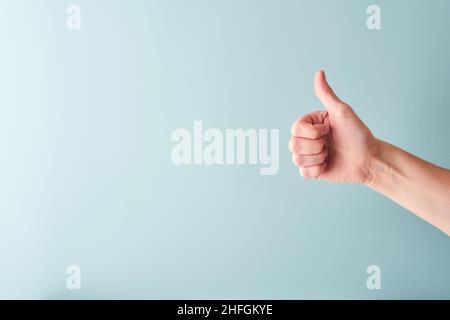 Weibliche Hand ok Zeichen auf hellblauem Hintergrund. Selektiver Fokus. Modell. Speicherplatz kopieren. Stockfoto