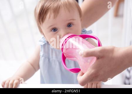 Kleinkind Baby Mädchen trinkt Wasser aus rosa sippy Tasse halten von ihrer Mutter Stockfoto