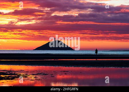 Der Sonnenaufgang am Strand von Ballynamona in der Grafschaft Cork, Irland, mit dem Leuchtturm von Ballycotton im Hintergrund Stockfoto