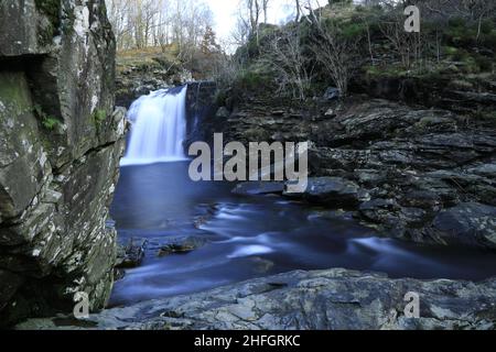 Der sanfte Fluss der Trossachs schlängelt sich friedlich durch üppige Landschaften, sein klares Wasser flüstert Geheimnisse des Friedens und der Harmonie Stockfoto