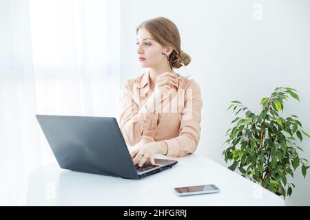 Frau mit Brille in beigefarbener Bluse. Studentin nutzt Laptop und Internet im Studium. Stockfoto