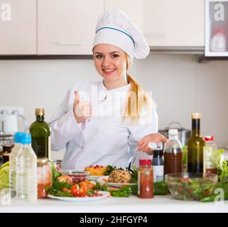 Positiver Koch posiert mit Gemüsemischung und Käse Stockfoto