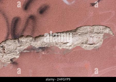 Zerbröckelnder, abblätternder Putz von der alten Fassade eines Stadthauses kaputtes, beschädigtes Gebäude. Stockfoto