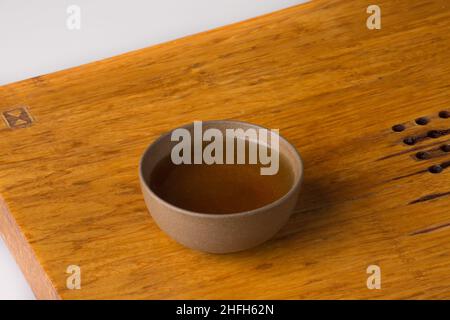 Eine Tasse frisch gebrühter pu-erh-Tee. Traditionelle Teetasse auf einem Holztisch für Teezeremonien. Stockfoto