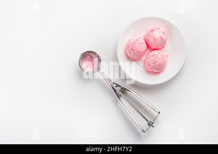 Drei Kugeln Beereneis und eine Kugel auf weißem Hintergrund mit Platz zum Kopieren. Erfrischendes Dessert. Draufsicht, Kopierbereich. Stockfoto