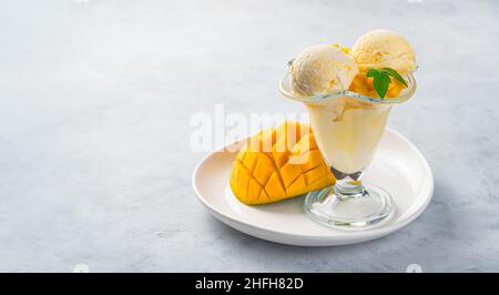 Mango-Eis und frische Mango auf grauem Hintergrund. Seitenansicht, Kopierbereich. Stockfoto