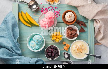 Eis verschiedener Art mit Früchten, Beeren und Schokolade auf einer blauen Tafel. Sommerdessert. Draufsicht. Stockfoto