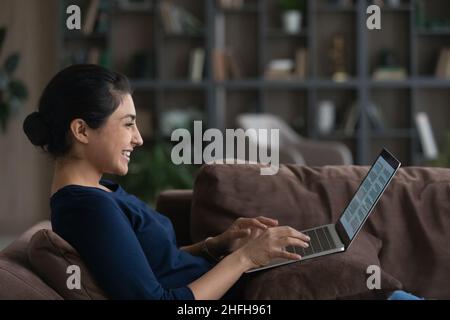 Glückliche junge indische Frau, die mit elektronischen Dokumenten arbeitet. Stockfoto