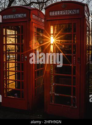 Wunderschönes Sonnenlicht durchbricht Londons ikonische rote Telefonboxen. Stockfoto