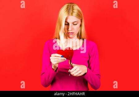 Trennung. Mädchen schneidet rotes Papier Herz mit einer Schere. Bruch von Beziehungen und Scheidung. Unglückliche Liebe. Stockfoto