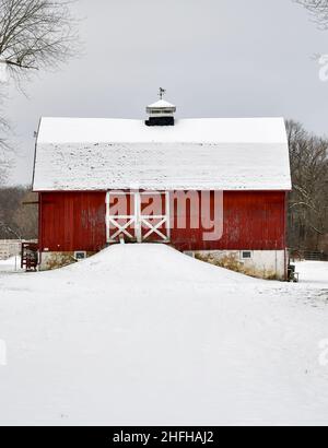 Vintage rote Scheune auf schneebedecktem Ackerland im Winter Stockfoto