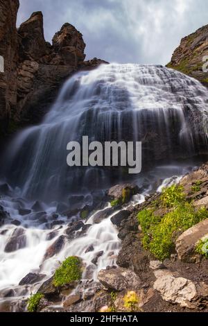 Majestätischer Wasserfall in den Bergen, ein Gebirgsfluss fällt von einer hohen Klippe auf Steine an einem sonnigen Tag, lange Exposition Stockfoto