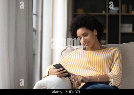 Entspannte junge afroamerikanische Frau mit Handy. Stockfoto