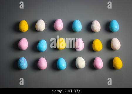 Bunte Osterschokoladeneier auf dunklem Hintergrund verstreut. Süßigkeiten, Leckereien. Stockfoto