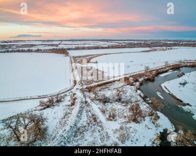 Abenddämmerung über dem South Platte River und Ackerland auf den Ebenen von Colorado in der Nähe von Milliken, Luftaufnahme mit Winterlandschaft Stockfoto