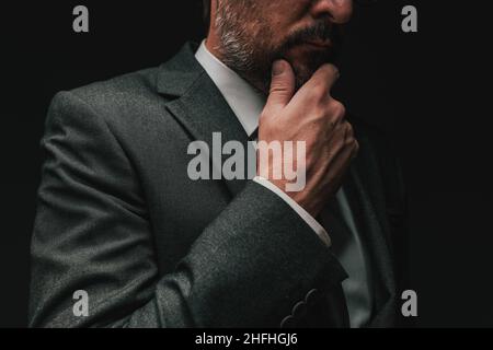 Überlegungen vor der Gründung eines Unternehmens, elegante Geschäftsmann in grauem Anzug denken und planen, Low-Key-Porträt mit selektivem Fokus Stockfoto