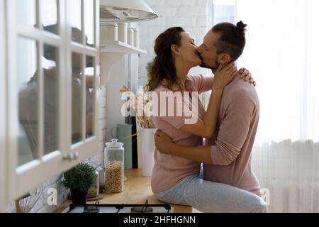 Glücklich leidenschaftliche junge Familie Paar zu Hause küssen. Stockfoto