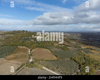 Luftpanorama auf den Hügeln des Val d'Orcia in der Nähe von Bagno Vignoni, Toskana, Italien. Toskanische Landschaft mit Zypressen, Weinbergen, Wäldern und gepflügten Stockfoto