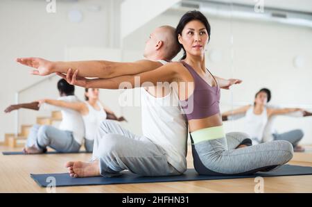 Athletische koreanische Frau, die mit einem männlichen Partner paarweise Yoga-Übungen durchführt Stockfoto