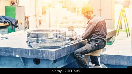 Fabrikarbeiter oder Techniker in hygienischer Maske und Hardhat arbeiten in pandemischen covid Zeiten am Weltplatz im Fabrikinneren. Stockfoto