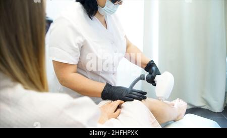 Nahaufnahme Einer Kosmetikerin, die im Beauty Spa das Bein der Frau wachst. Prozess Enthaarung weibliche Beine und Hände in einem Schönheitssalon. Nahaufnahme, die von einer Beautici einwachsen Stockfoto