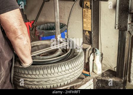 Mann, der in einer Werkstatt mit Elektrowerkzeugen Kabel vom Rad entfernt Stockfoto