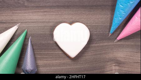 Großer weißer herzförmiger Keks mit Eiszapfen für den Muttertag, den Womans-Tag oder den Valentinstag auf Holzhintergrund. Speicherplatz kopieren Stockfoto